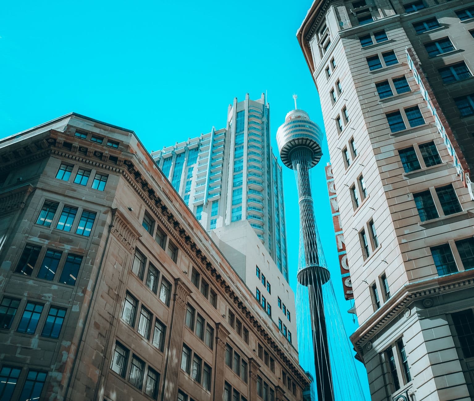 Low-angle view of Sydney's CBD skyscrapers and Sydney Tower under clear blue sky