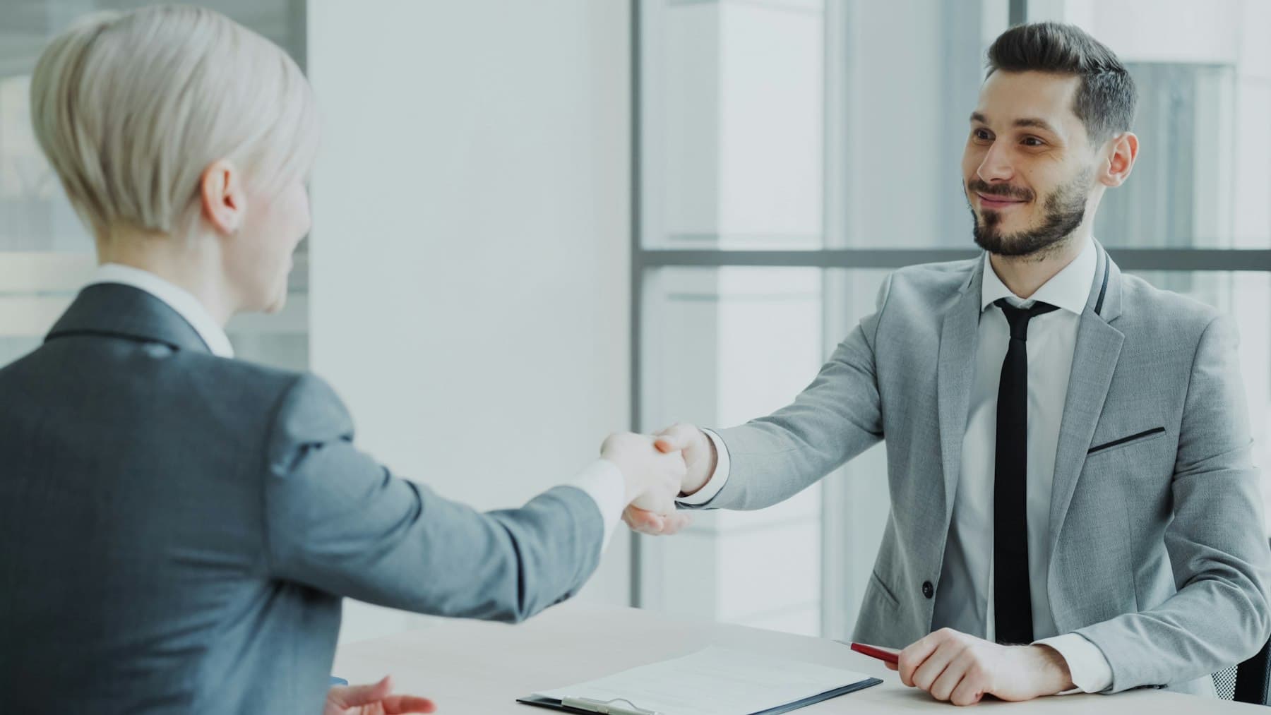Client and adviser shaking hands across a meeting table
